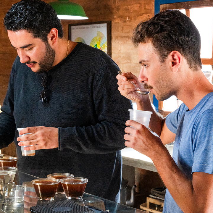 Two men tasting coffee in a bar setting